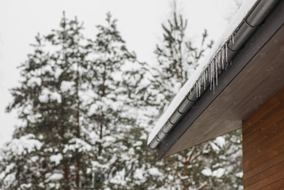 An ice dam and icicles built up along the eave of a home in winter